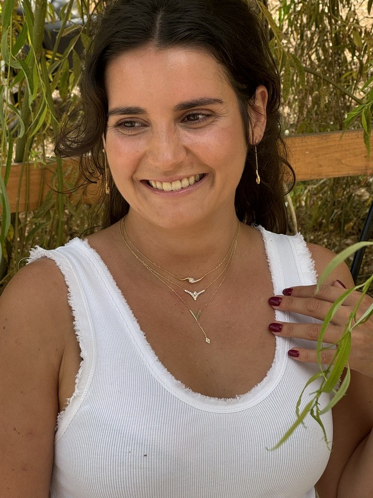 Smiling under a willow tree wearing the Curved Marquise, V Bird and V Pendant necklaces layered in 18k gold