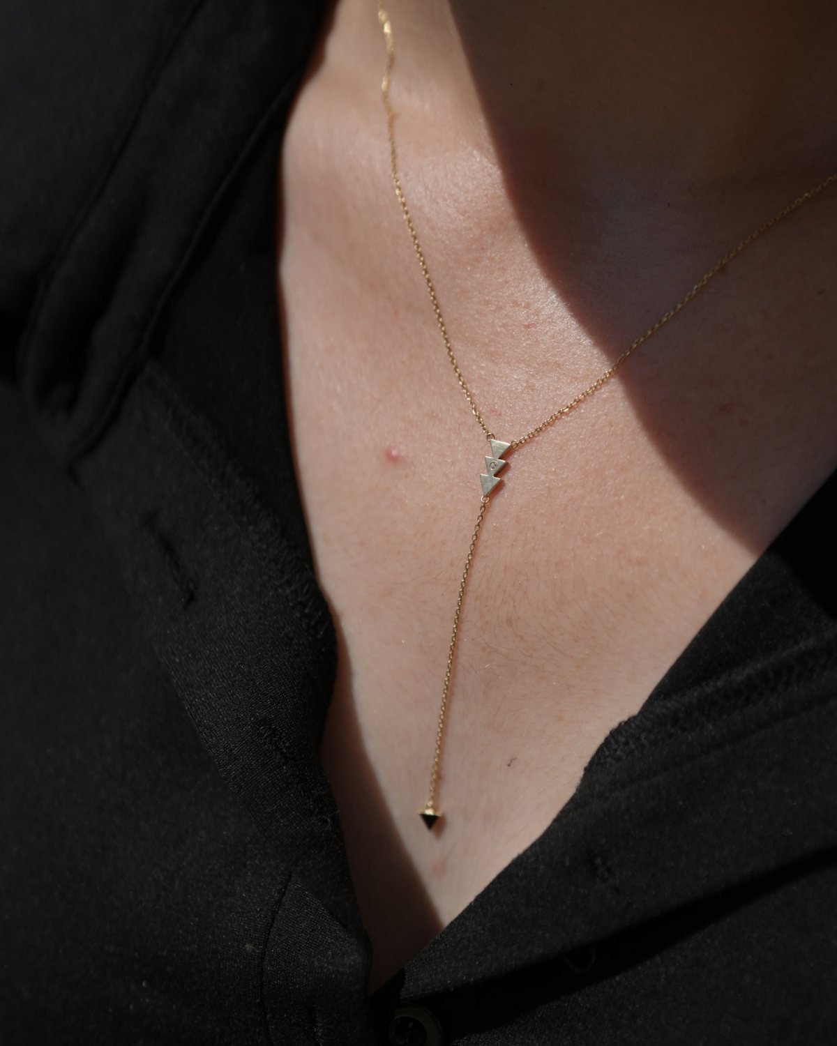 Y-shaped gold arrow necklace worn with a black top