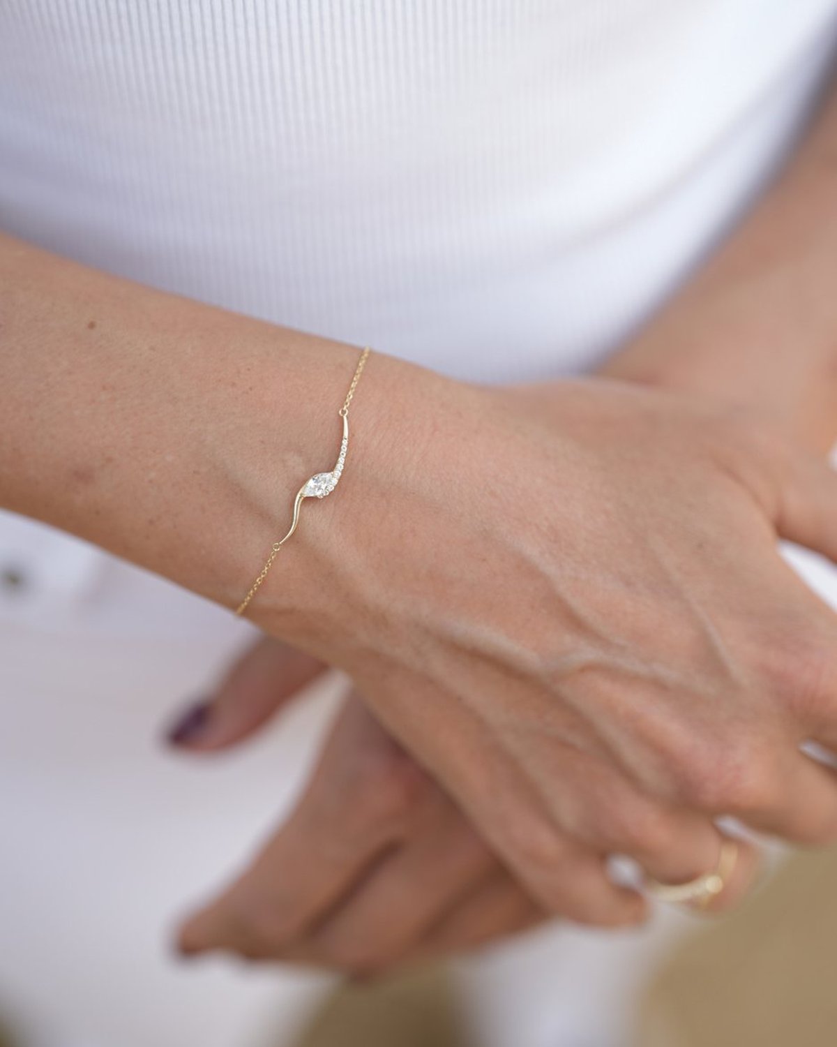 Gold curved marquise bracelet on the wrist