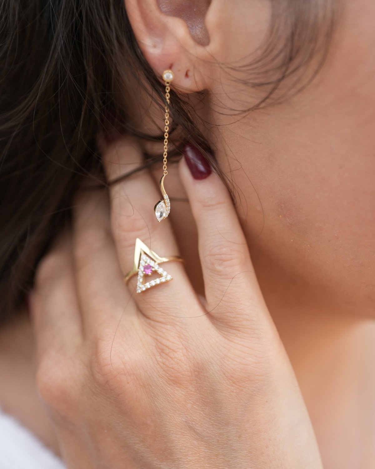 Gold curved marquise drop earrings displayed on a portrait vase