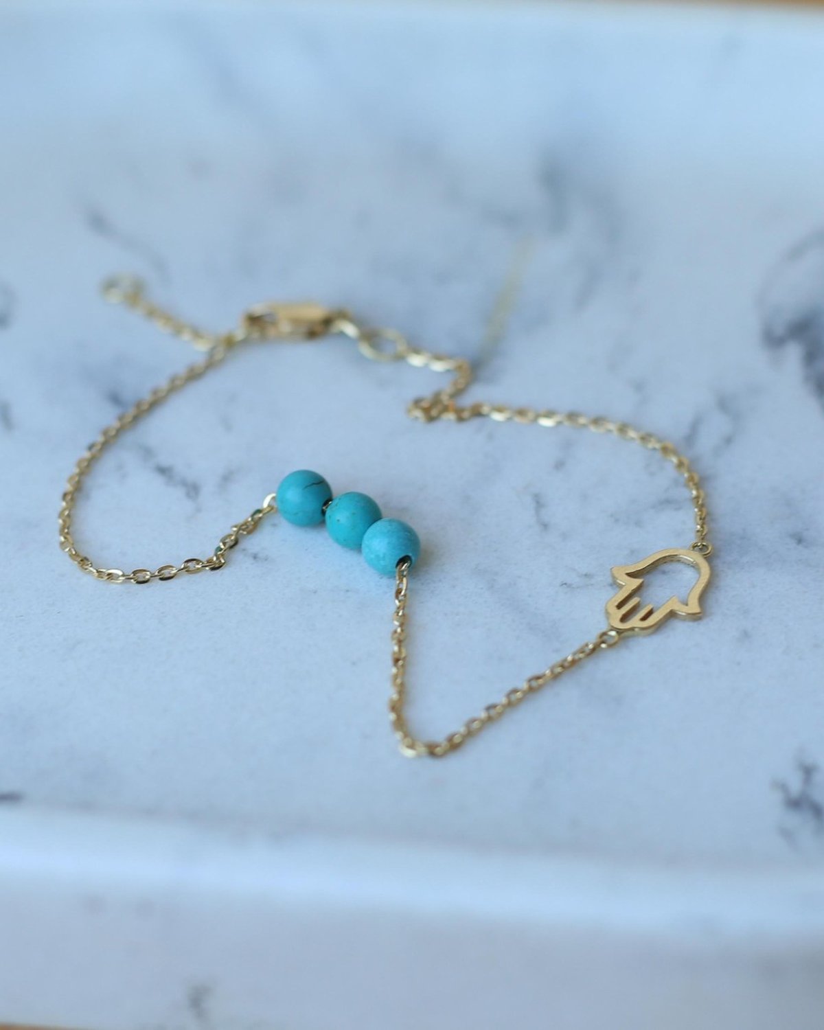 Gold Fatima anklet with blue freshwater pearls, laid out with other pieces