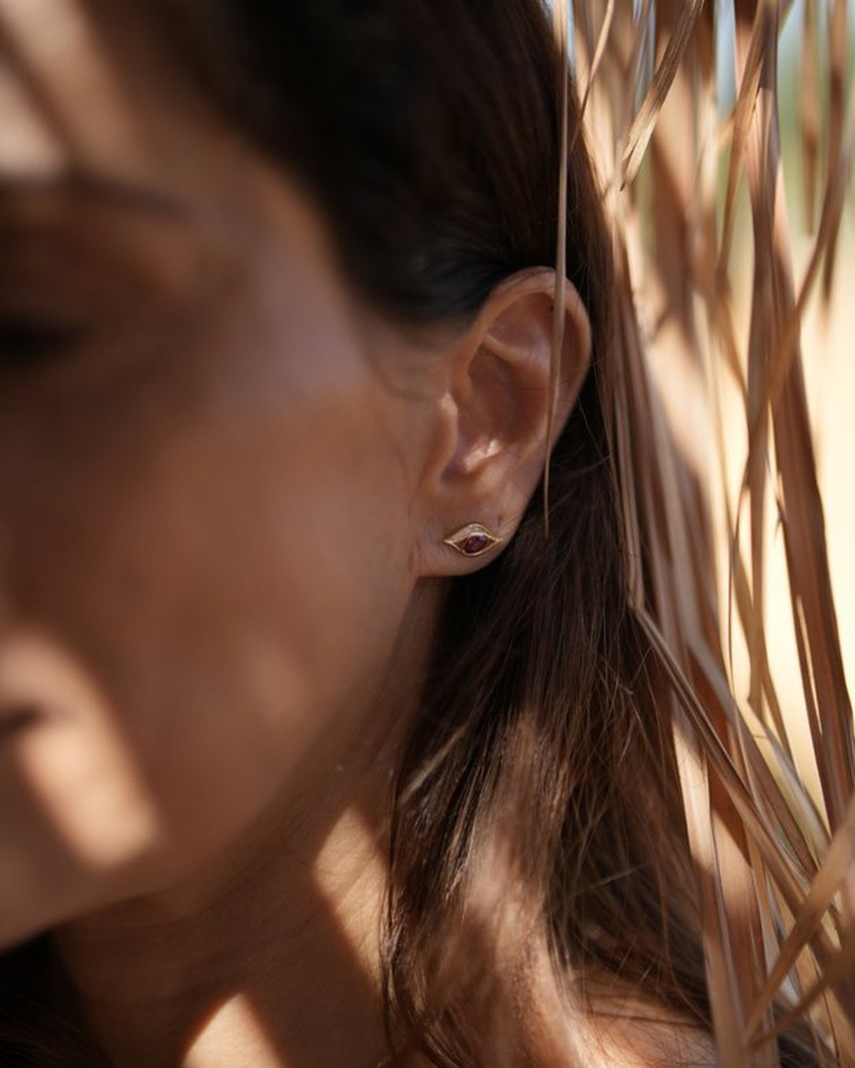 Gold horse eye stud earring, worn on the ear