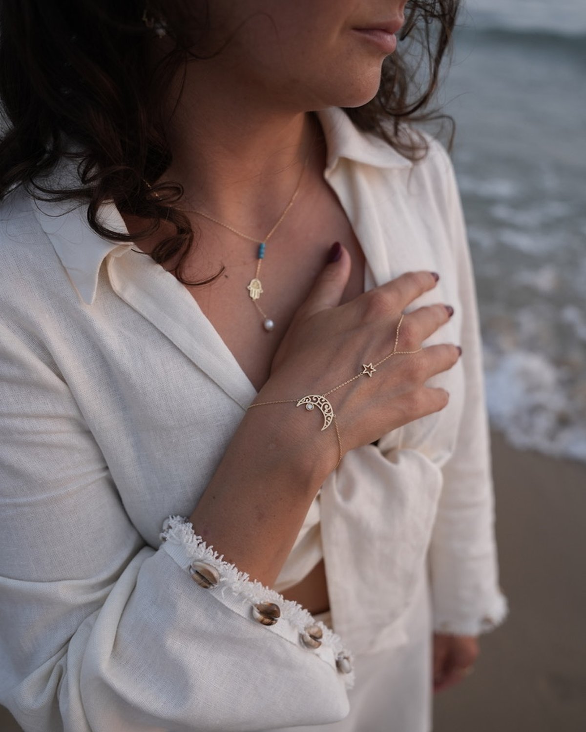 Gold moon and star hand chain, worn with a white shirt