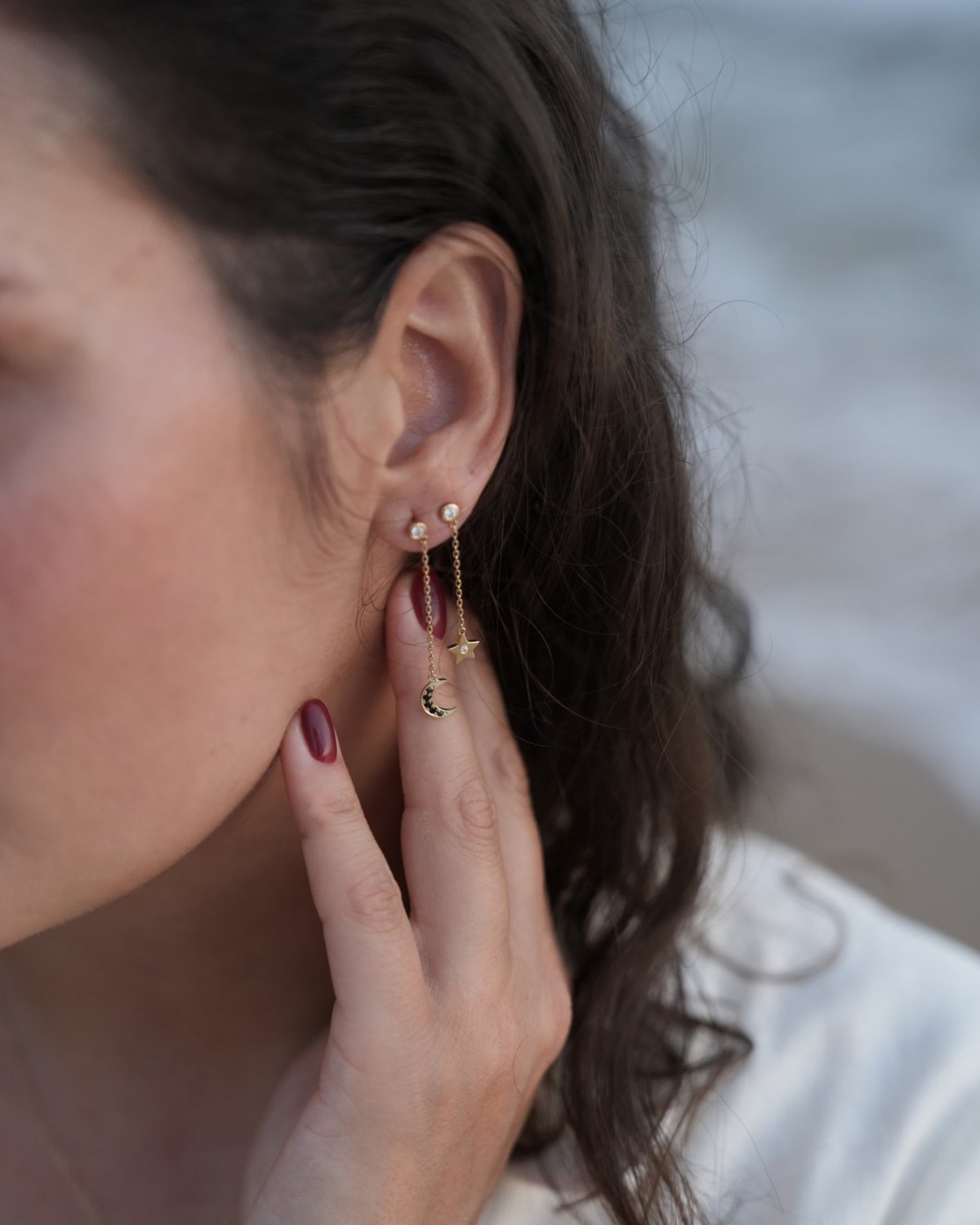 Gold moon and star drop earring, worn by the sea