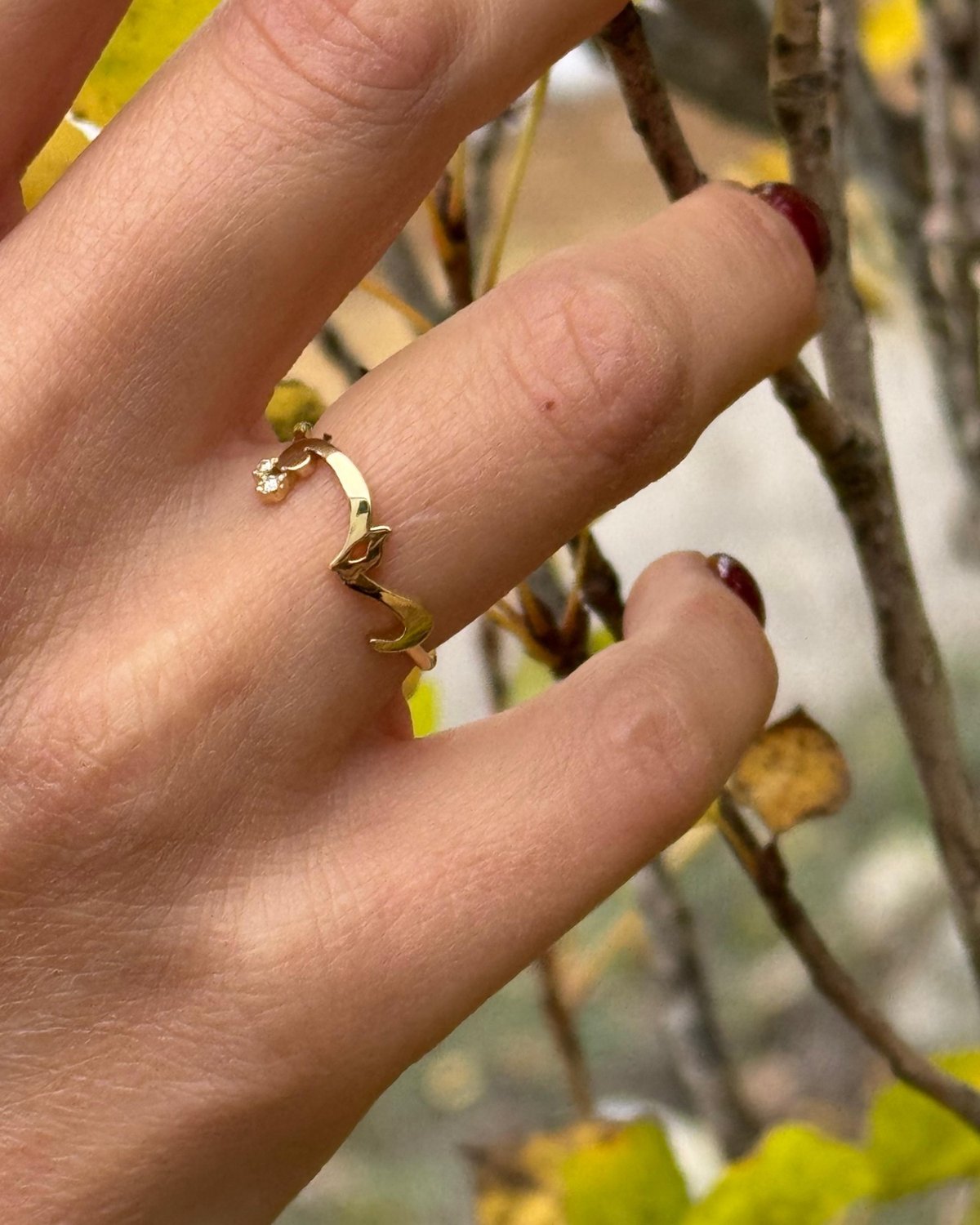 Gold ring spelling qamar in Arabic, among white roses