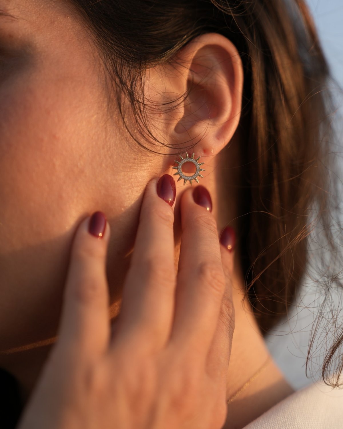 Gold sun stud earring with white zircon, worn