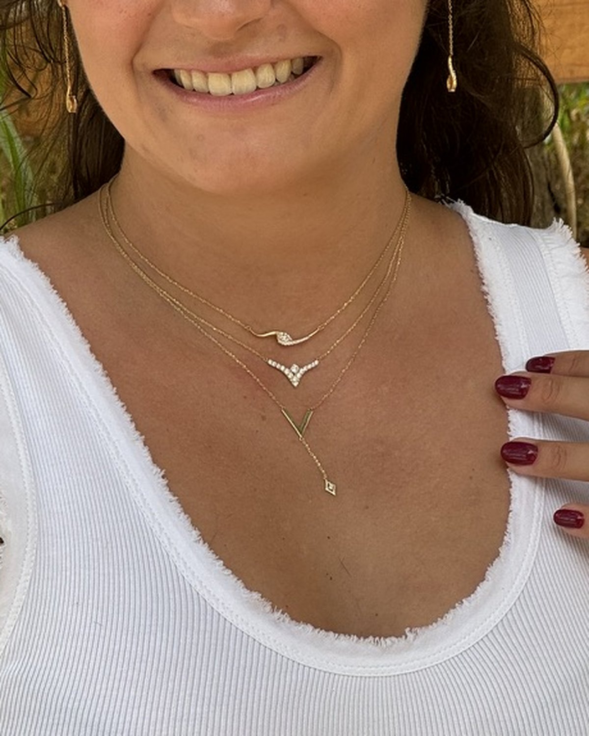 Gold V bird necklace set with white zircon, on an open book