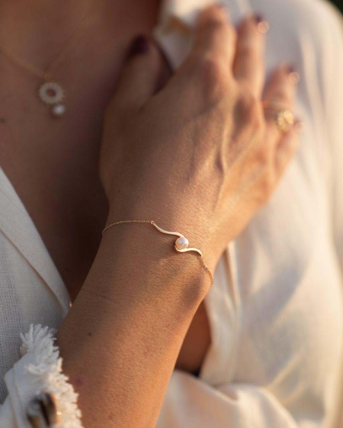 Gold wave bracelet with a pearl, on the wrist